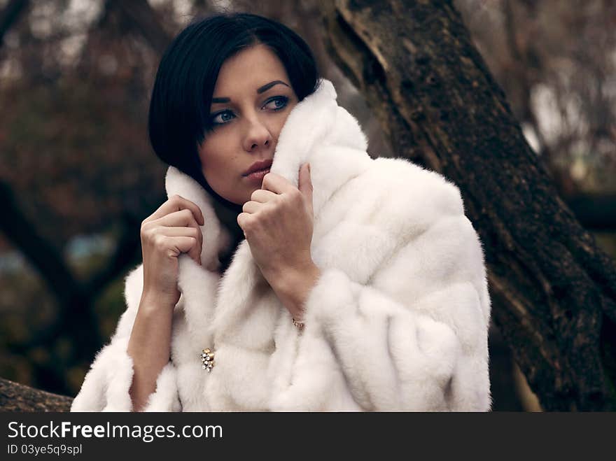 Elegant girl with black hair in white coat with high collar. Elegant girl with black hair in white coat with high collar