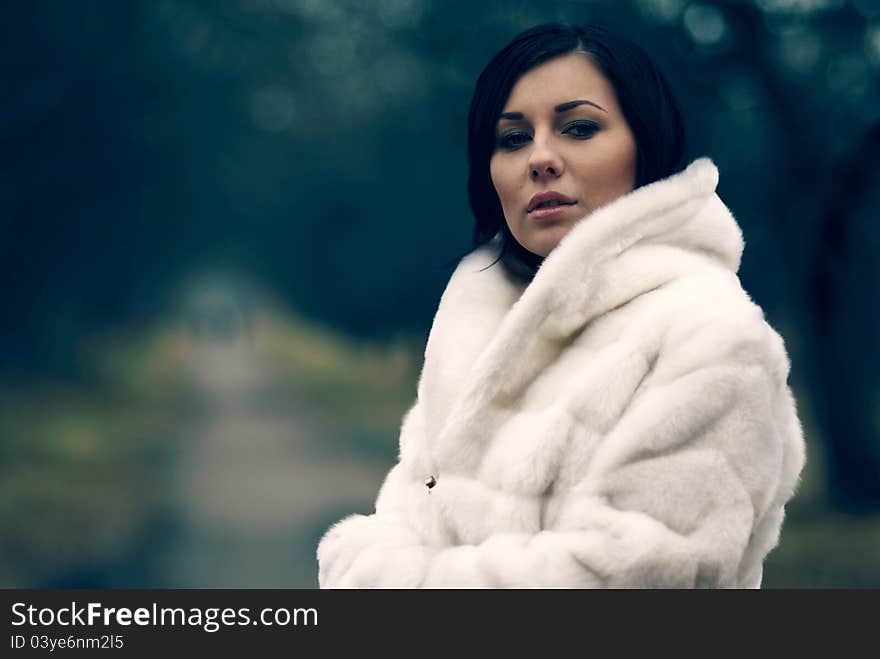 Elegant girl with black hair in white coat with high collar. Elegant girl with black hair in white coat with high collar