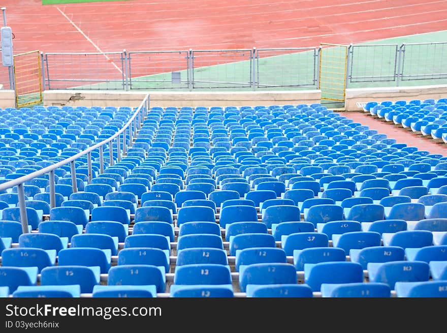 Blue empty plastic chairs at the stadium