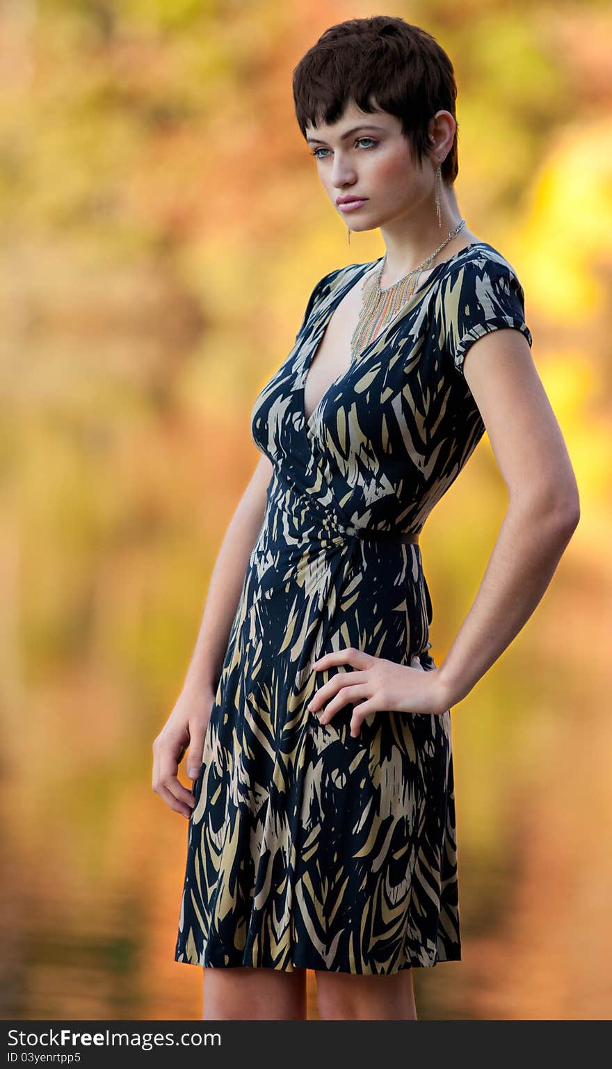 A portrait of a beautiful model in an elegant outfit, standing outside in fall with gorgeous fall colors behind. A portrait of a beautiful model in an elegant outfit, standing outside in fall with gorgeous fall colors behind