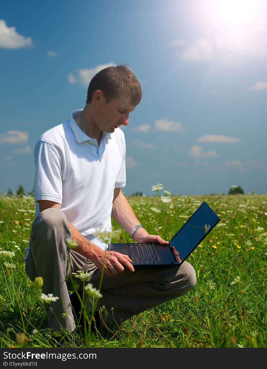 Mobile man working on notebook in the meadow