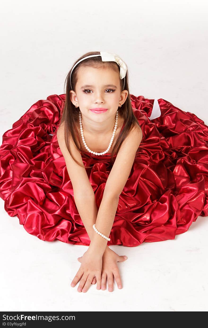 Beautiful little girl in red evening dress on white background