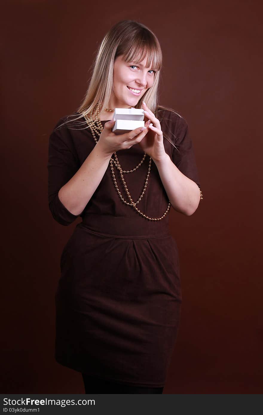 Beautiful young woman in fashionable dress with a gift. Beautiful young woman in fashionable dress with a gift