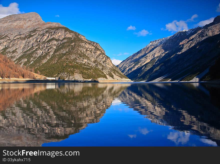 High mountains reflecting on a calm lake during sunny day. High mountains reflecting on a calm lake during sunny day.