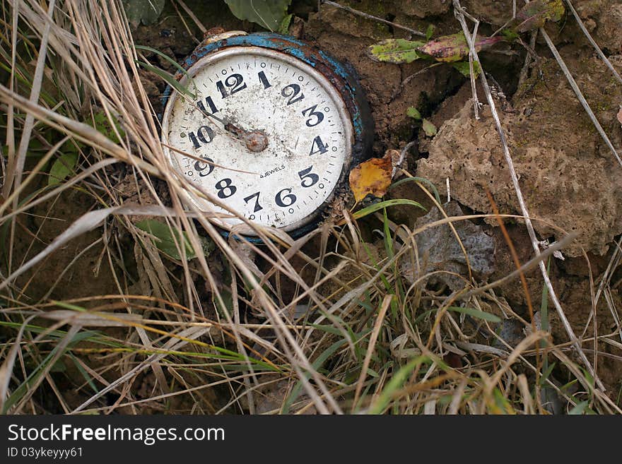 An old antique broken clock lying on the ground. An old antique broken clock lying on the ground