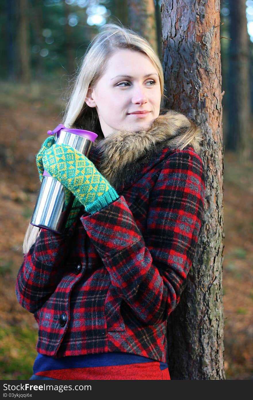 Woman in the woods drinking tea from a thermos cup. Woman in the woods drinking tea from a thermos cup