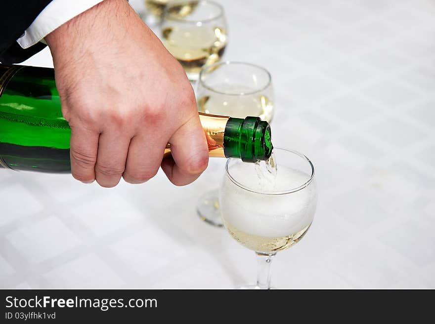 Pouring of champagne glasses on white table