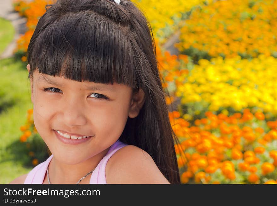 Little asian girl smile with shallow focus on flowers background. Little asian girl smile with shallow focus on flowers background