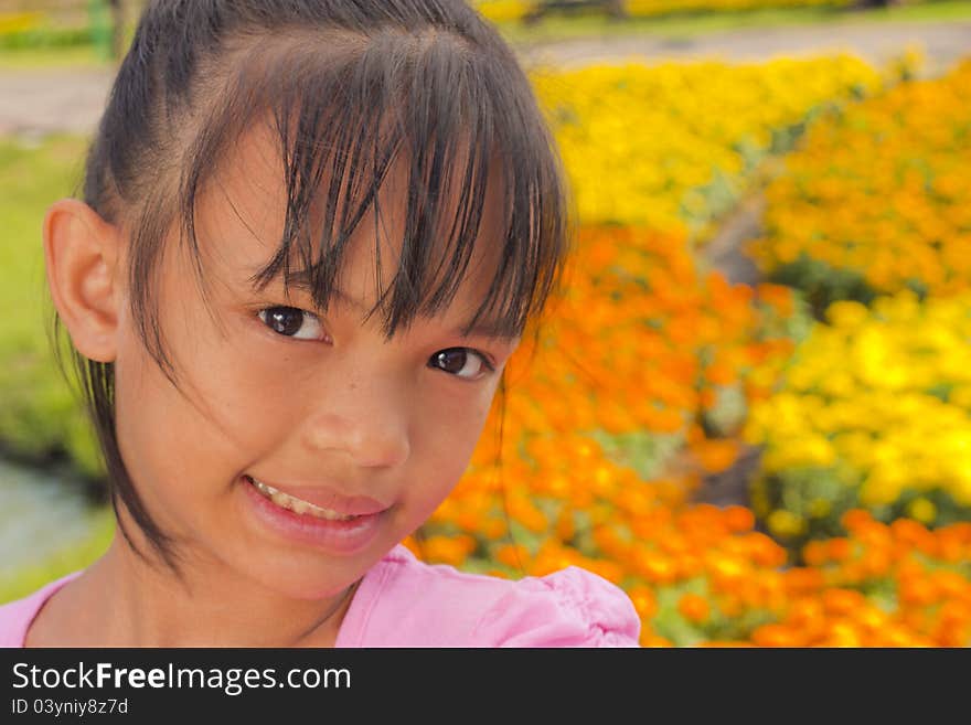 Little asian girl smile with shallow focus on flowers background. Little asian girl smile with shallow focus on flowers background