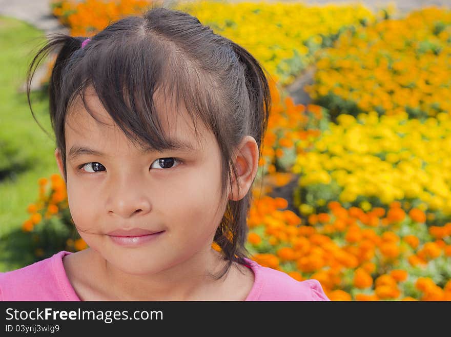 Little asian girl smile with shallow focus on flowers background. Little asian girl smile with shallow focus on flowers background