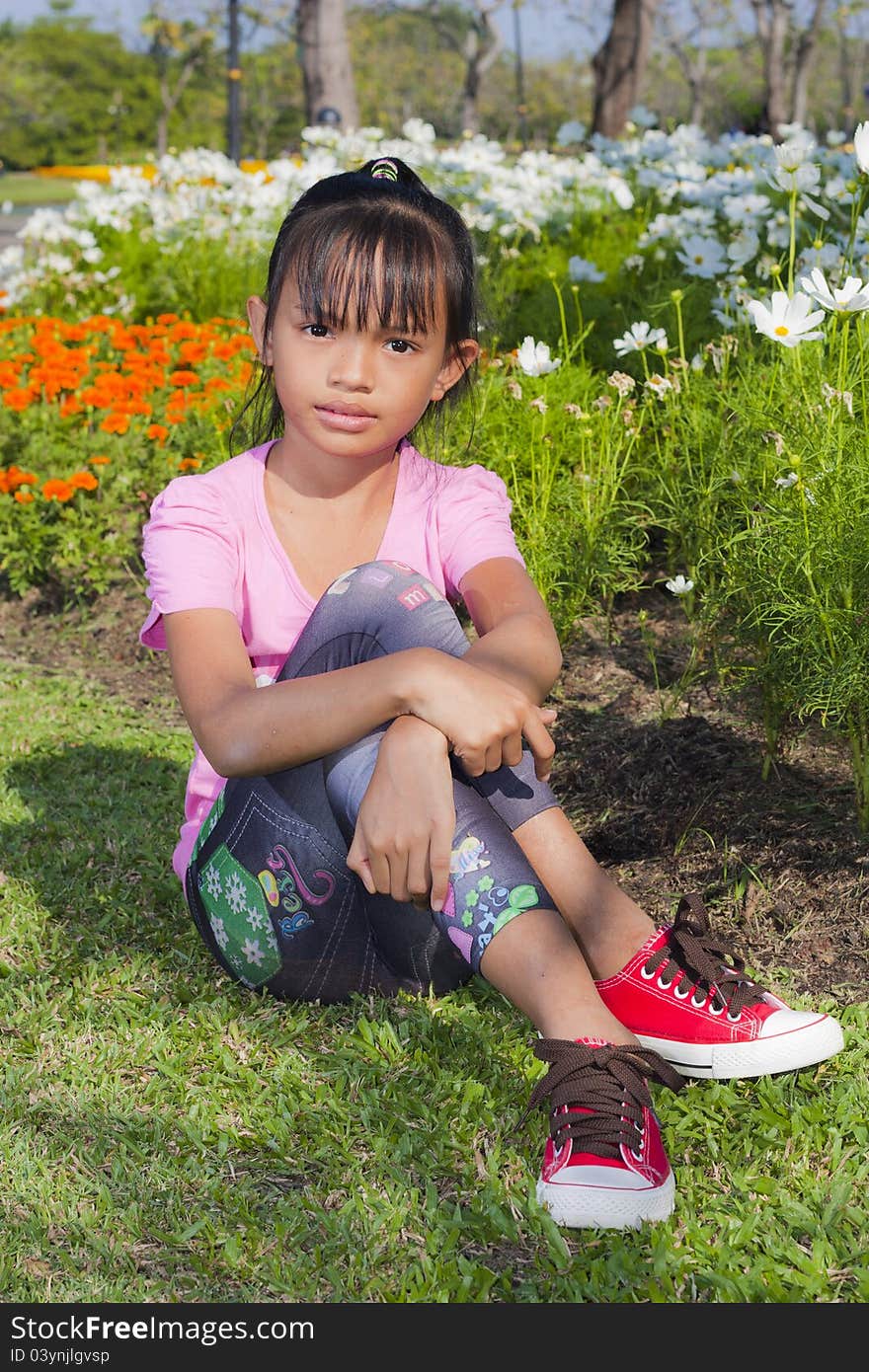 Little asian girl smile with shallow focus on flowers background. Little asian girl smile with shallow focus on flowers background