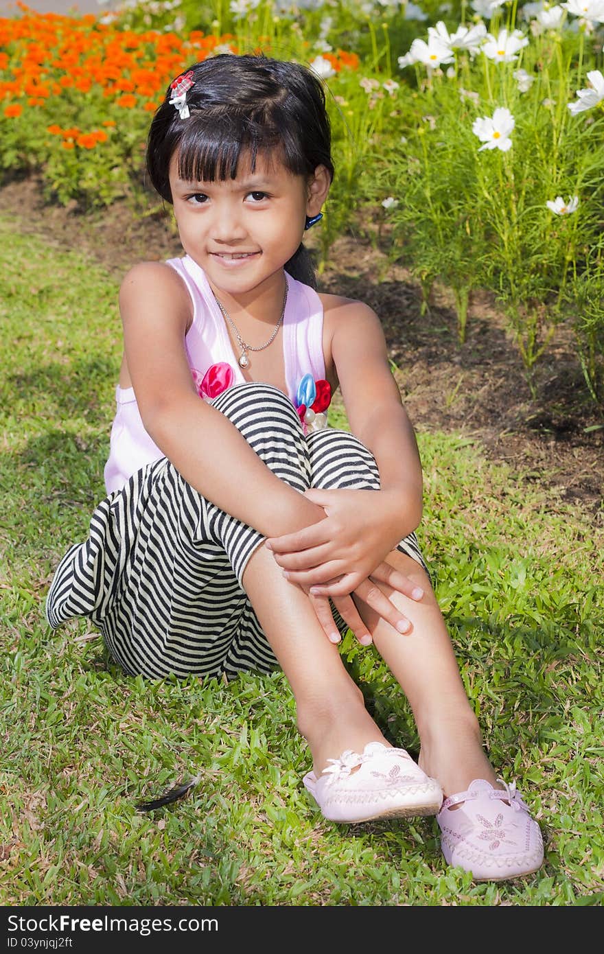 Little asian girl smile with shallow focus on flowers background. Little asian girl smile with shallow focus on flowers background