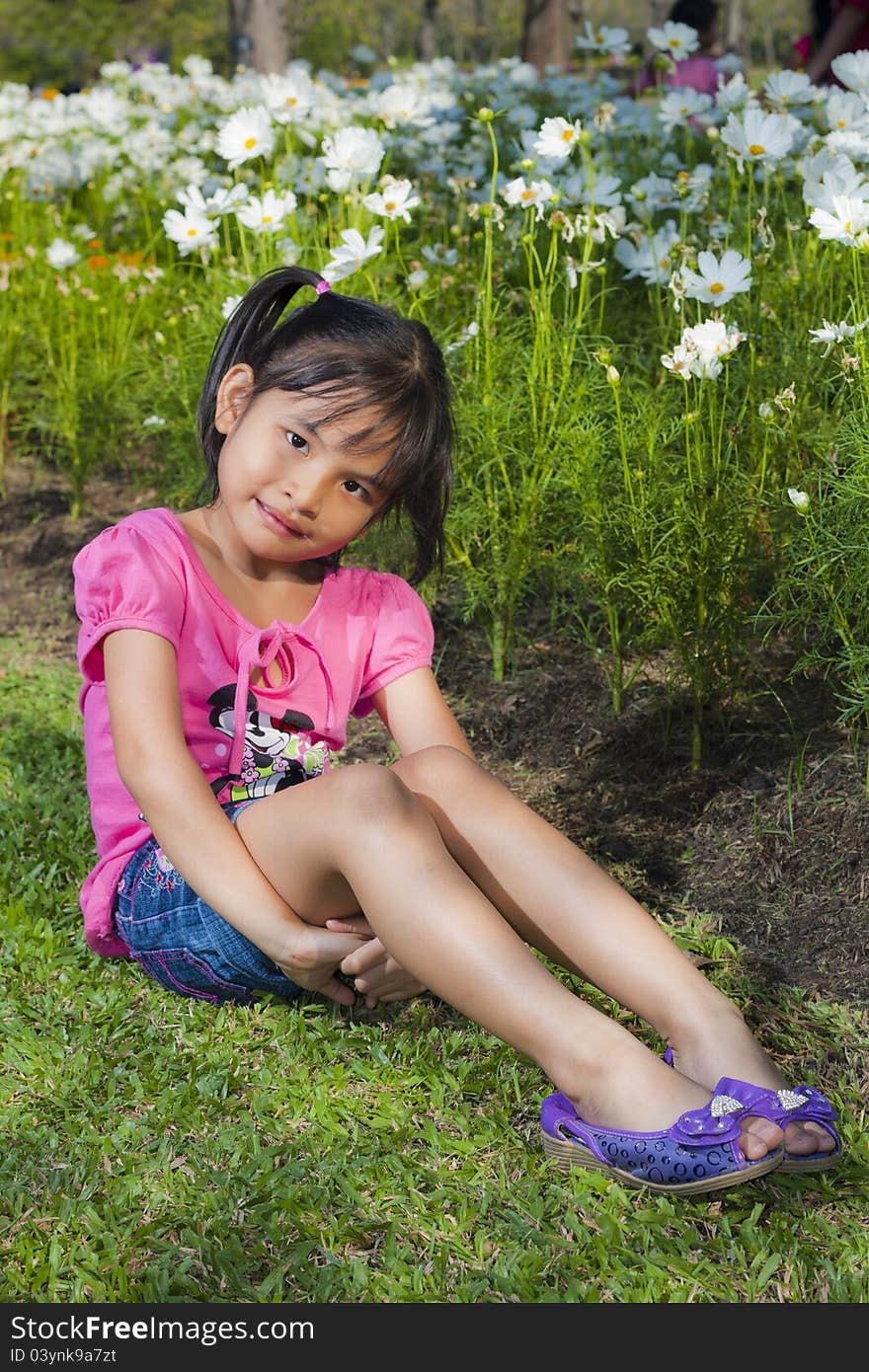 Little asian girl smile with shallow focus on flowers background. Little asian girl smile with shallow focus on flowers background