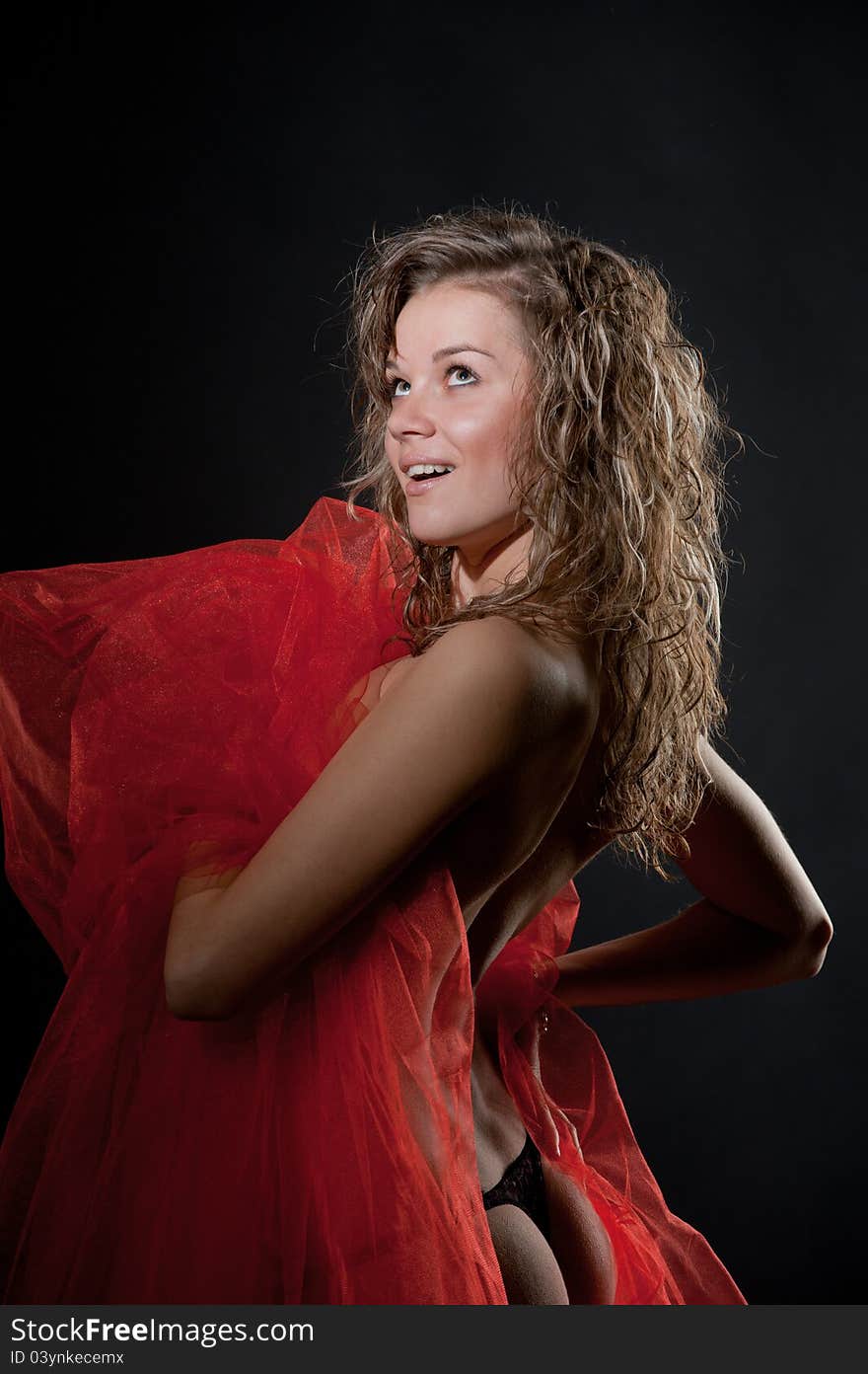 Portrait of naked pretty girl showing sexy back and buttocks with red nylon in the hands in studio. Portrait of naked pretty girl showing sexy back and buttocks with red nylon in the hands in studio