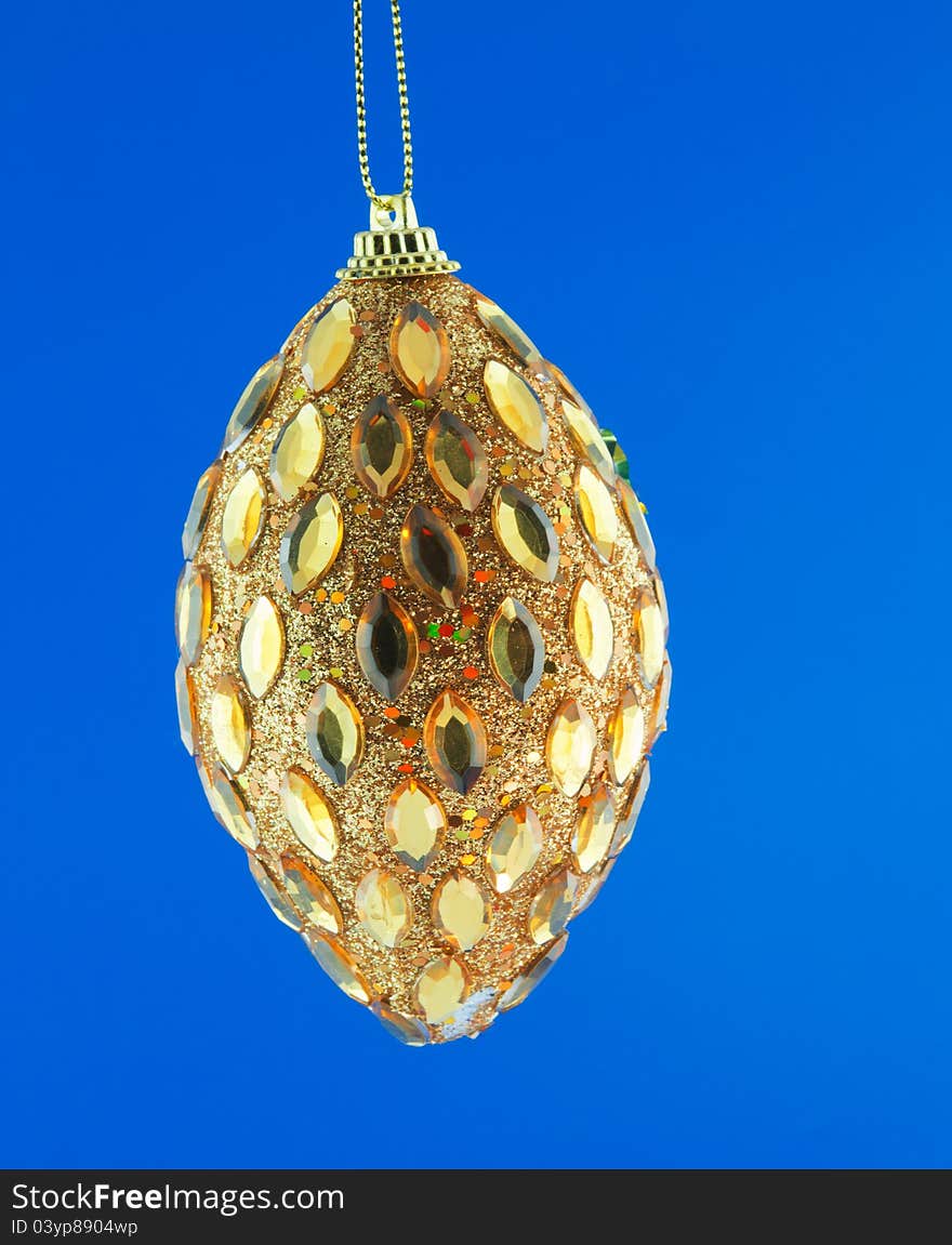 Gold cone, Christmas decorations hanging on a golden thread against the blue background. Gold cone, Christmas decorations hanging on a golden thread against the blue background