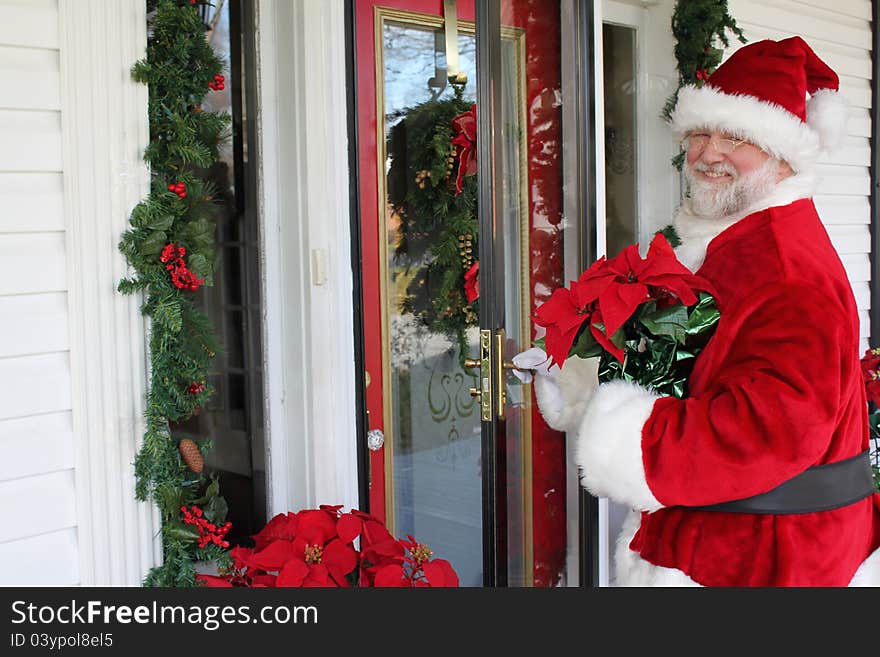 Santa Claus in front of a door decorated for Christmas. Santa Claus in front of a door decorated for Christmas.