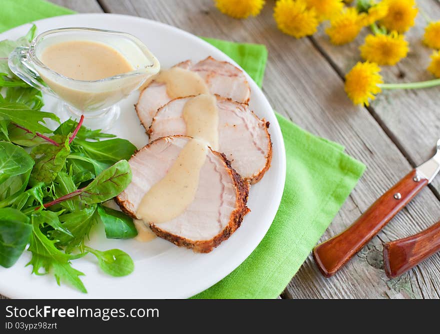 Roasted pork slices with apple and curry sauce and green salad on the plate