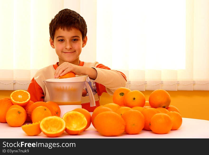 A boy making ( press out ) fresh orange juice surrounded with many oranges. A boy making ( press out ) fresh orange juice surrounded with many oranges