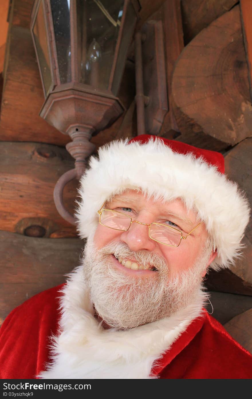 Santa Claus in front of a log cabin with an antique looking lantern above his head. Santa Claus in front of a log cabin with an antique looking lantern above his head.