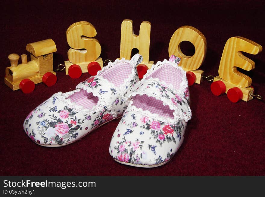 Baby shoes for a little girl with wooden toy train in the background. Baby shoes for a little girl with wooden toy train in the background