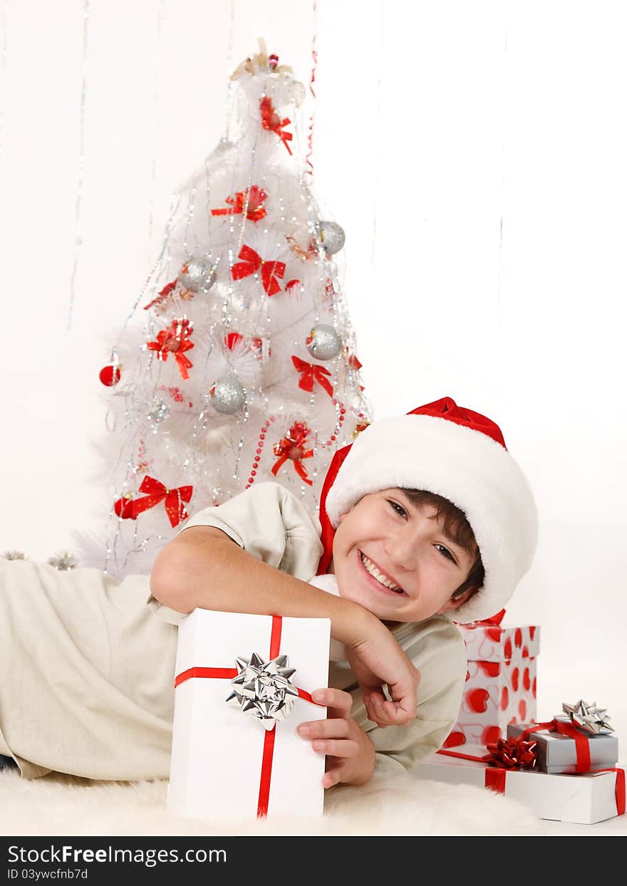 Cheerful child with Christmas gifts and a Christmas tree on a white background