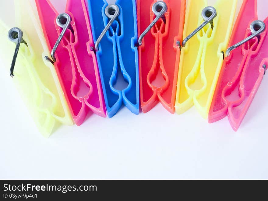 Colored clothes pegs in sequence on white background