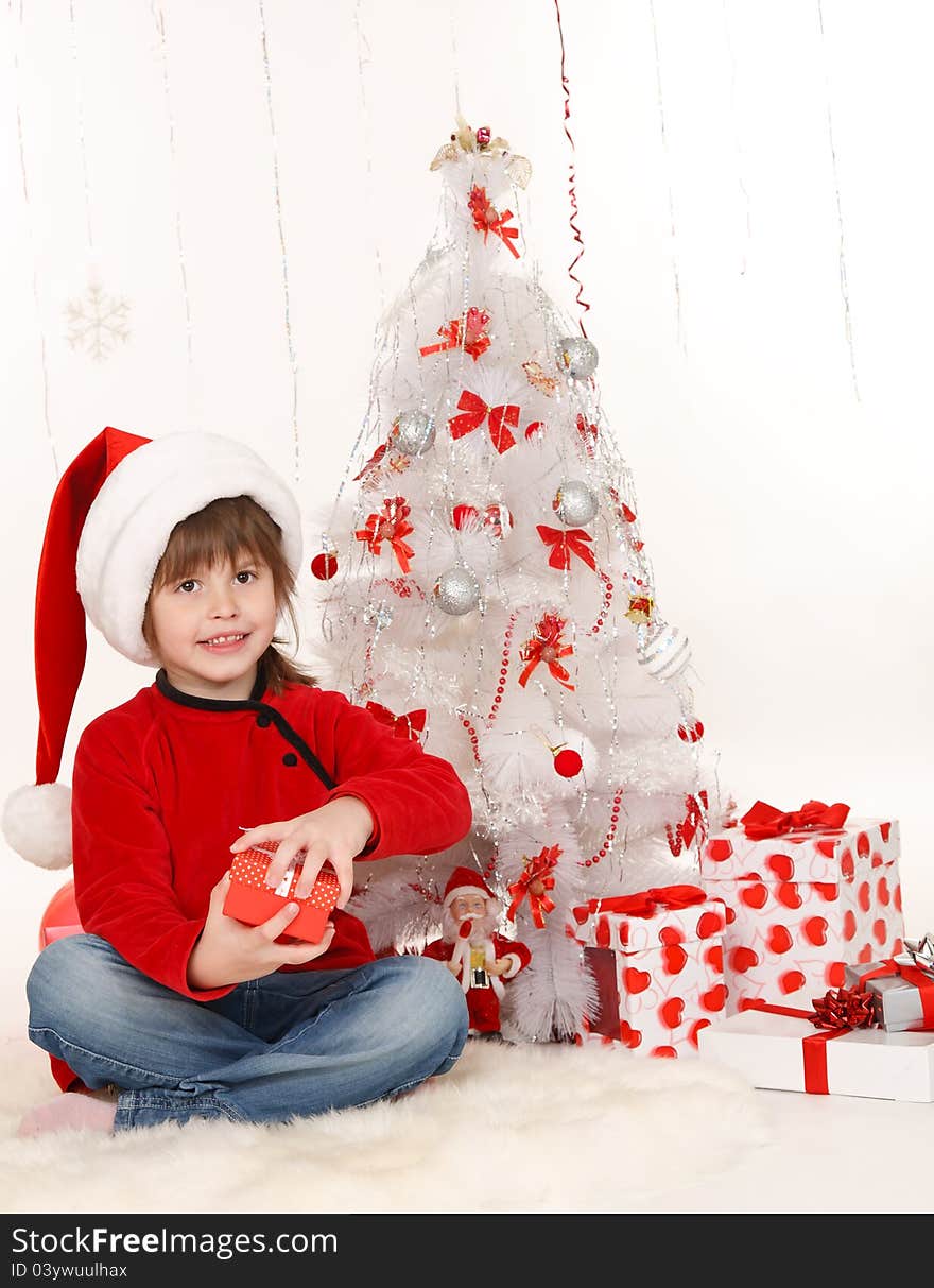 Little girl with a Christmas gift sitting beside Christmas tree. Little girl with a Christmas gift sitting beside Christmas tree