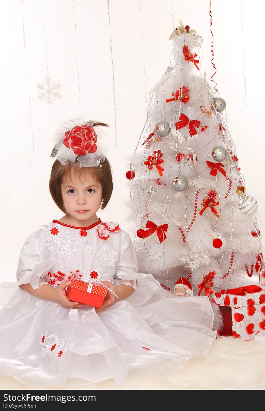 Little girl with a Christmas gift sitting beside Christmas tree. Little girl with a Christmas gift sitting beside Christmas tree