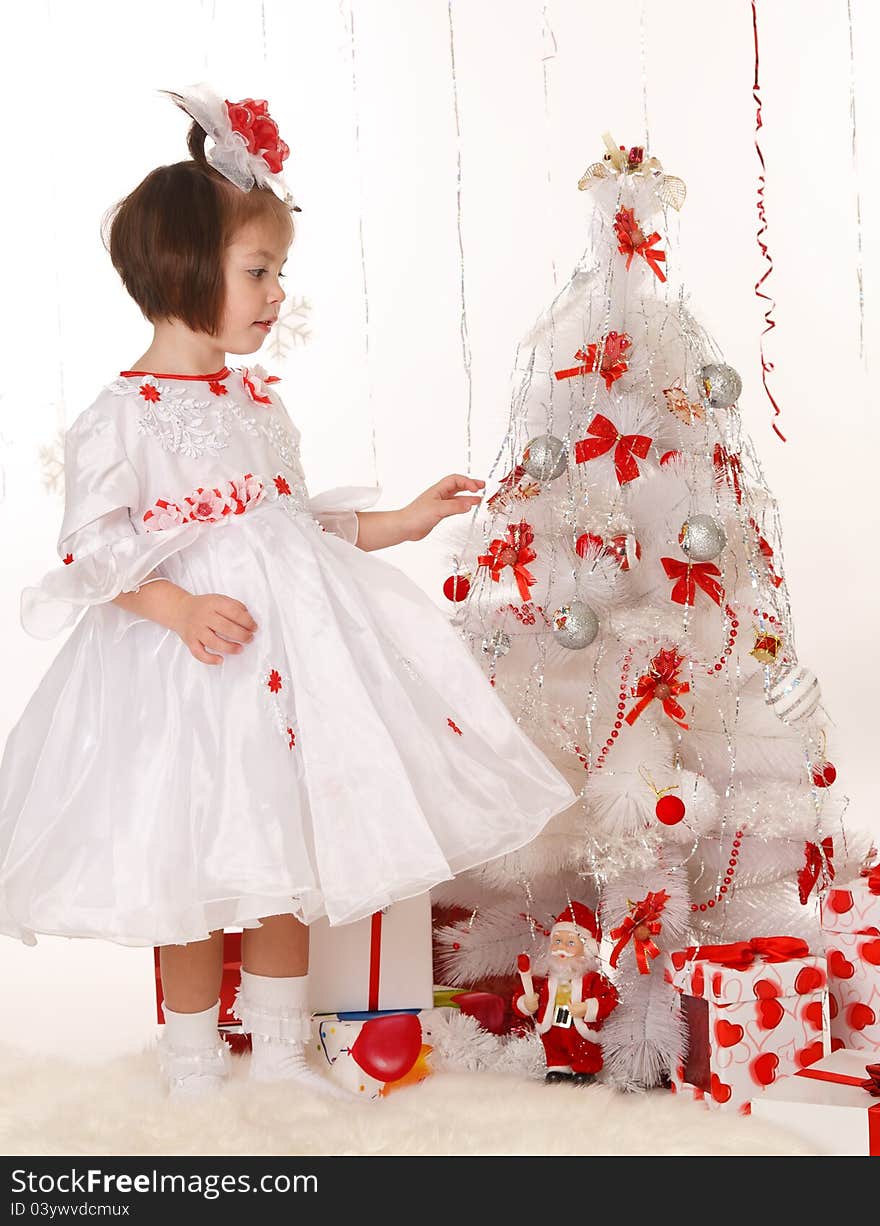 Little girl in a beautiful dress standing near a Christmas tree. Little girl in a beautiful dress standing near a Christmas tree
