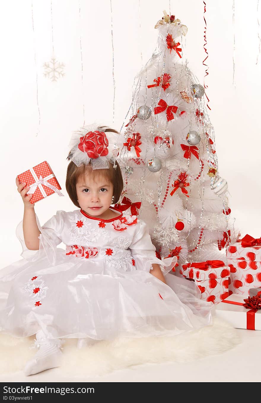 Little girl with a Christmas gift sitting beside Christmas tree. Little girl with a Christmas gift sitting beside Christmas tree