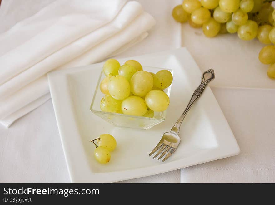 White grapes lying on a plate with a small plug.