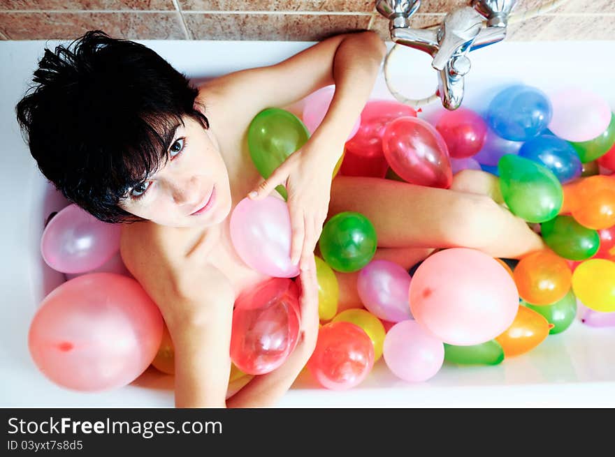 Woman playing with balloons in her bathtub