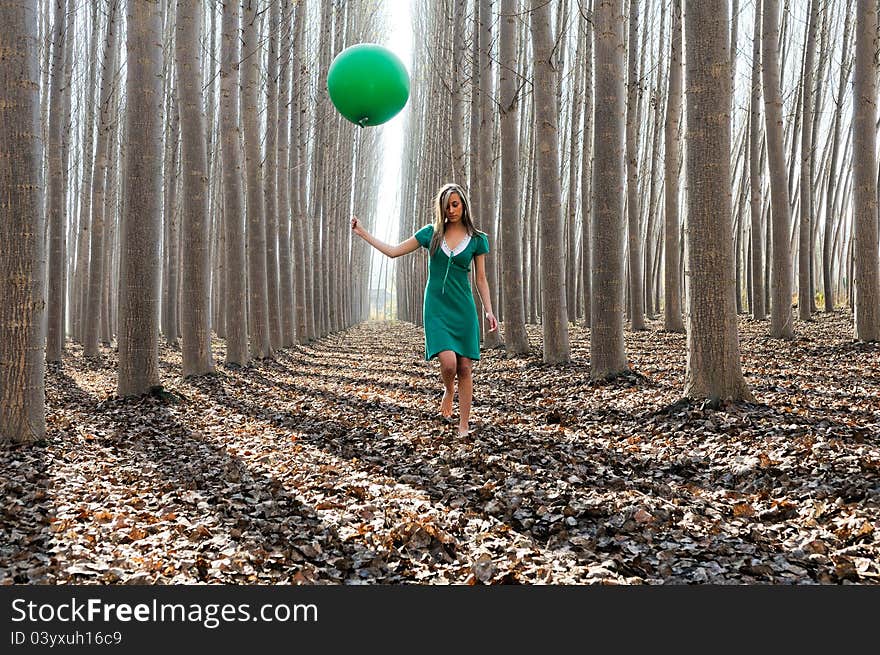 Beautiful blonde girl, dressed in green, walking into the forest. Beautiful blonde girl, dressed in green, walking into the forest