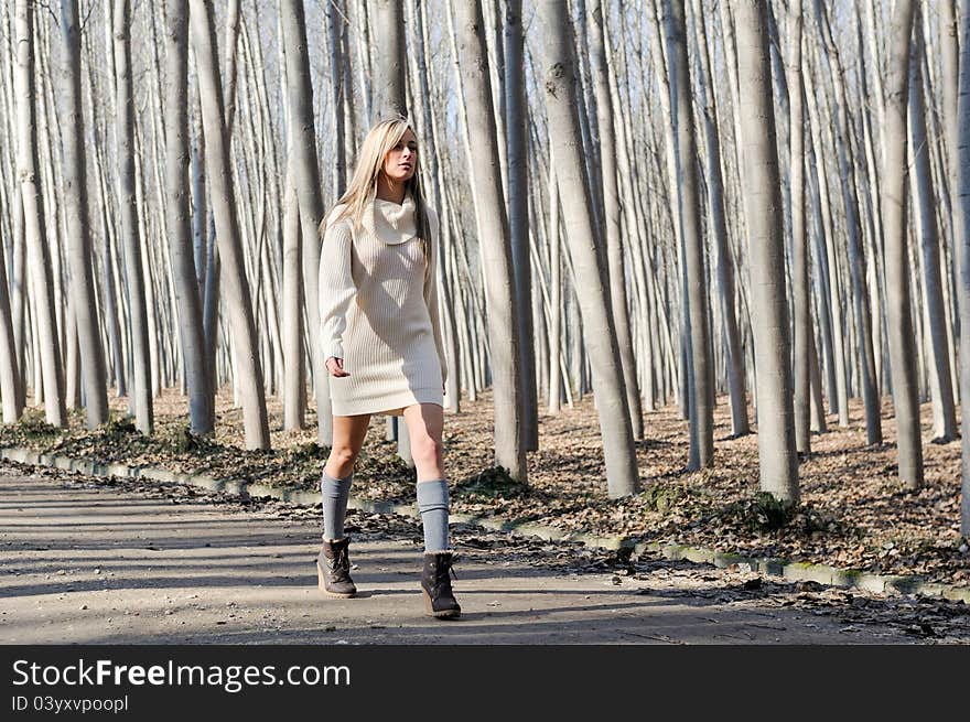 Beautiful blonde girl, dressed with beige dress, walking in a rural road. Beautiful blonde girl, dressed with beige dress, walking in a rural road