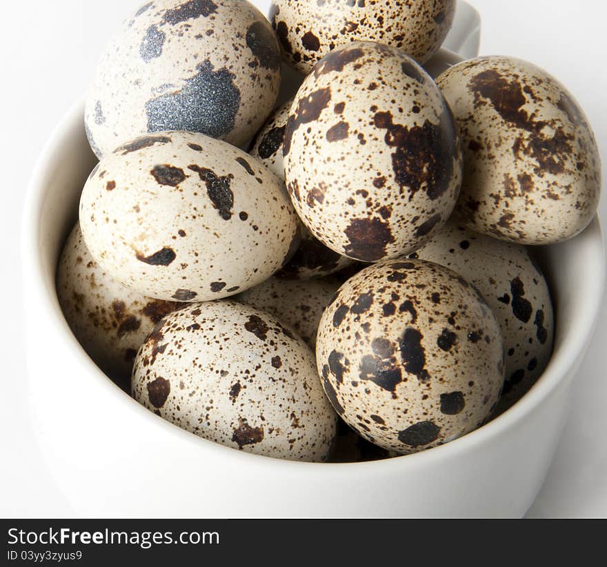 The quail eggs in bowl on white background