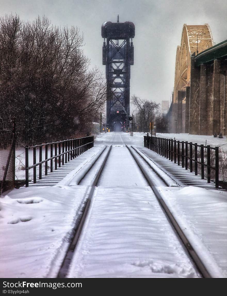 A railroad bridge that runs alongside the International Bridge which connects Sault Ste. Marie, Michigan to Sault Ste. Marie Ontario, Canada on a snowy day. A railroad bridge that runs alongside the International Bridge which connects Sault Ste. Marie, Michigan to Sault Ste. Marie Ontario, Canada on a snowy day.