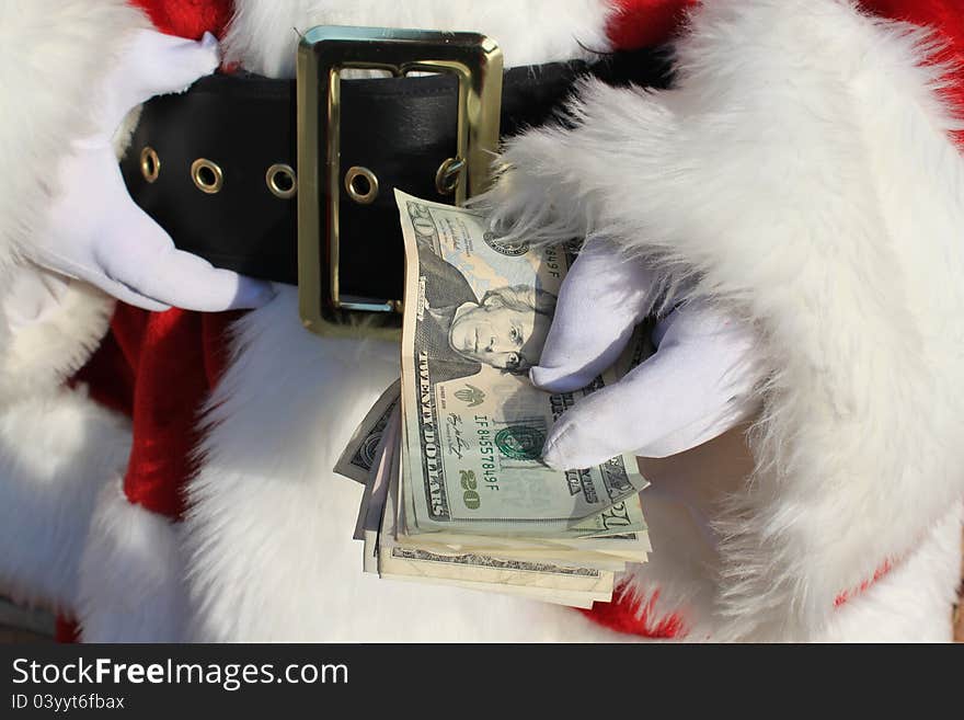 Santa Claus' gloved hand holding a stack of cash. Santa Claus' gloved hand holding a stack of cash.