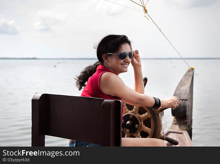 A happy young girl, wearing sun glasses and red top, enjoying nature while sailing house boat. A happy young girl, wearing sun glasses and red top, enjoying nature while sailing house boat