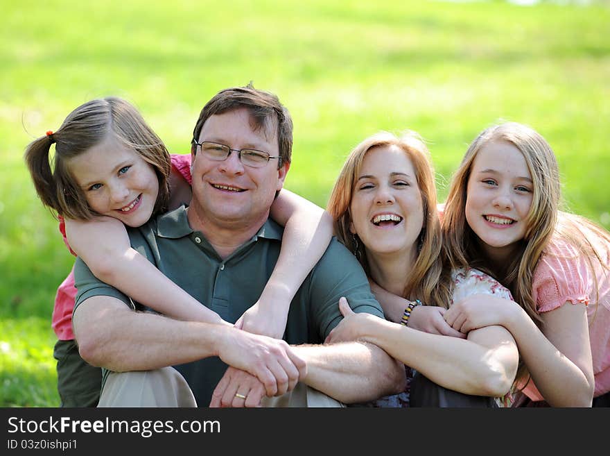 Young Couple with daughters smiling and hugging outdoors