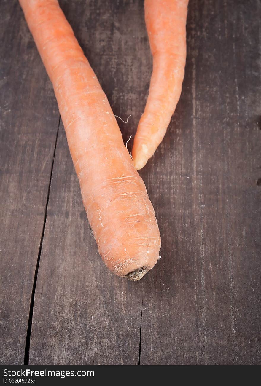 Two fresh carrots on plank