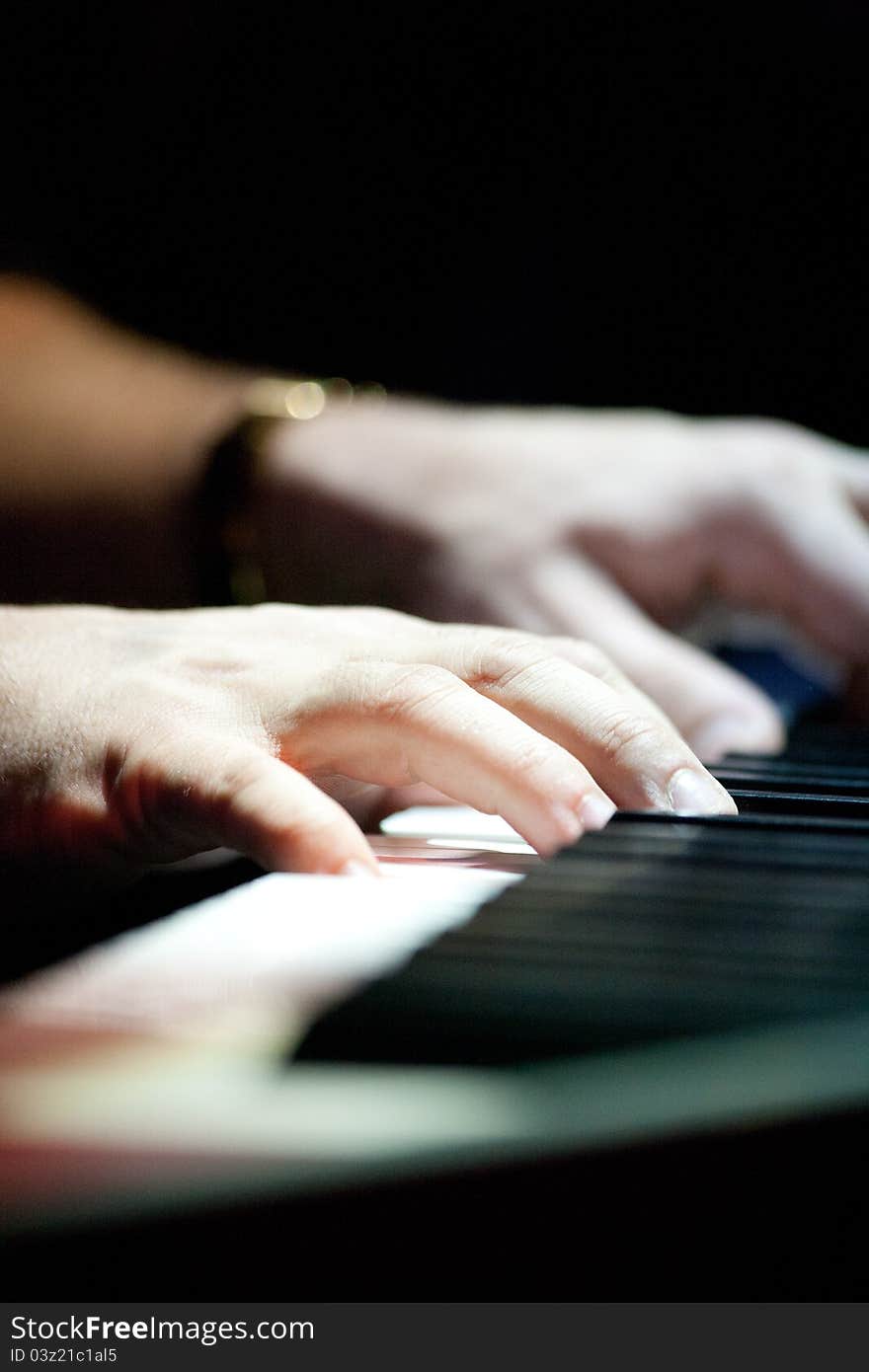 A detail of a mans hands playing the piano.