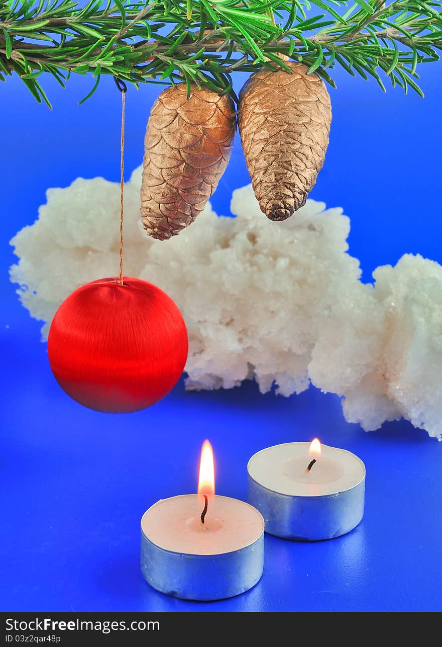 Red balls, cone spruce, ice and sprigs to decorate and candles burning for Christmas, against a blue background. Red balls, cone spruce, ice and sprigs to decorate and candles burning for Christmas, against a blue background