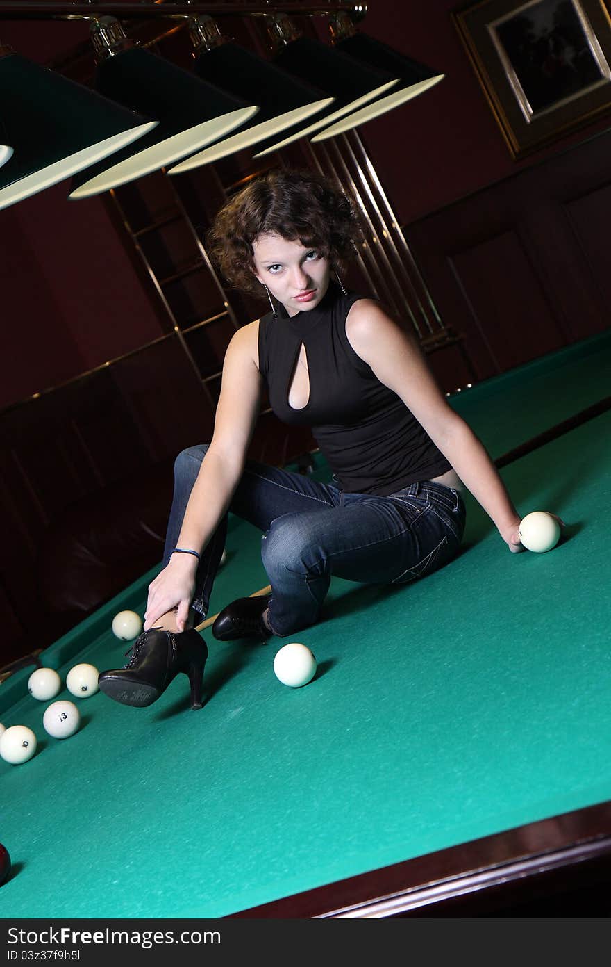 The beautiful blonde aims in the course of game at billiards. The beautiful blonde aims in the course of game at billiards