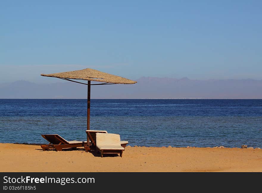 Sunshade and sun loungers on the Red Sea shore. Sunshade and sun loungers on the Red Sea shore