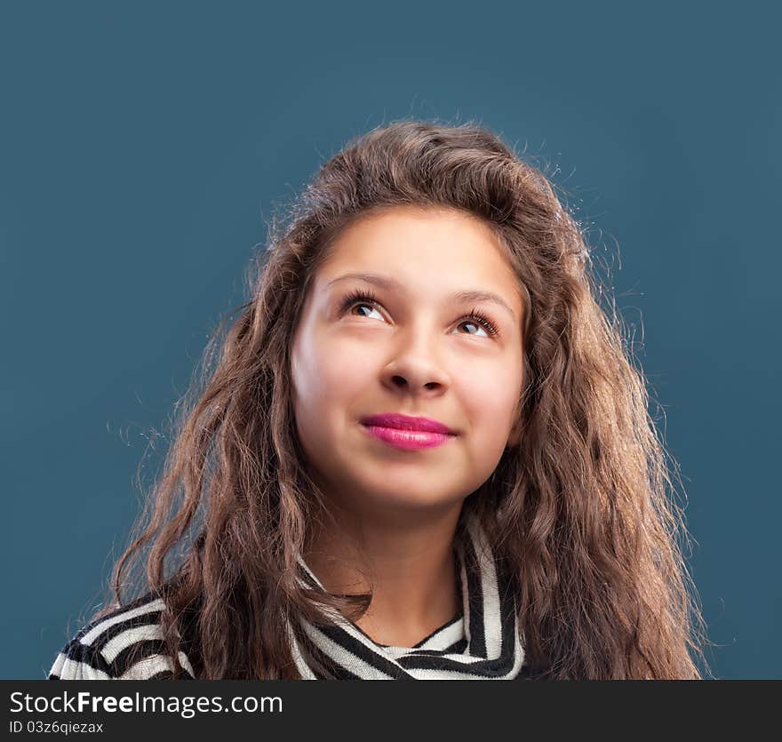 Beautiful young girl looking up isolated on blue background