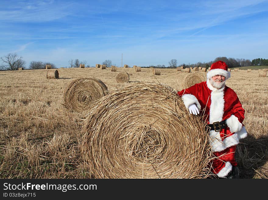 Santa standing against a bale of hay in a hay field. Santa standing against a bale of hay in a hay field.