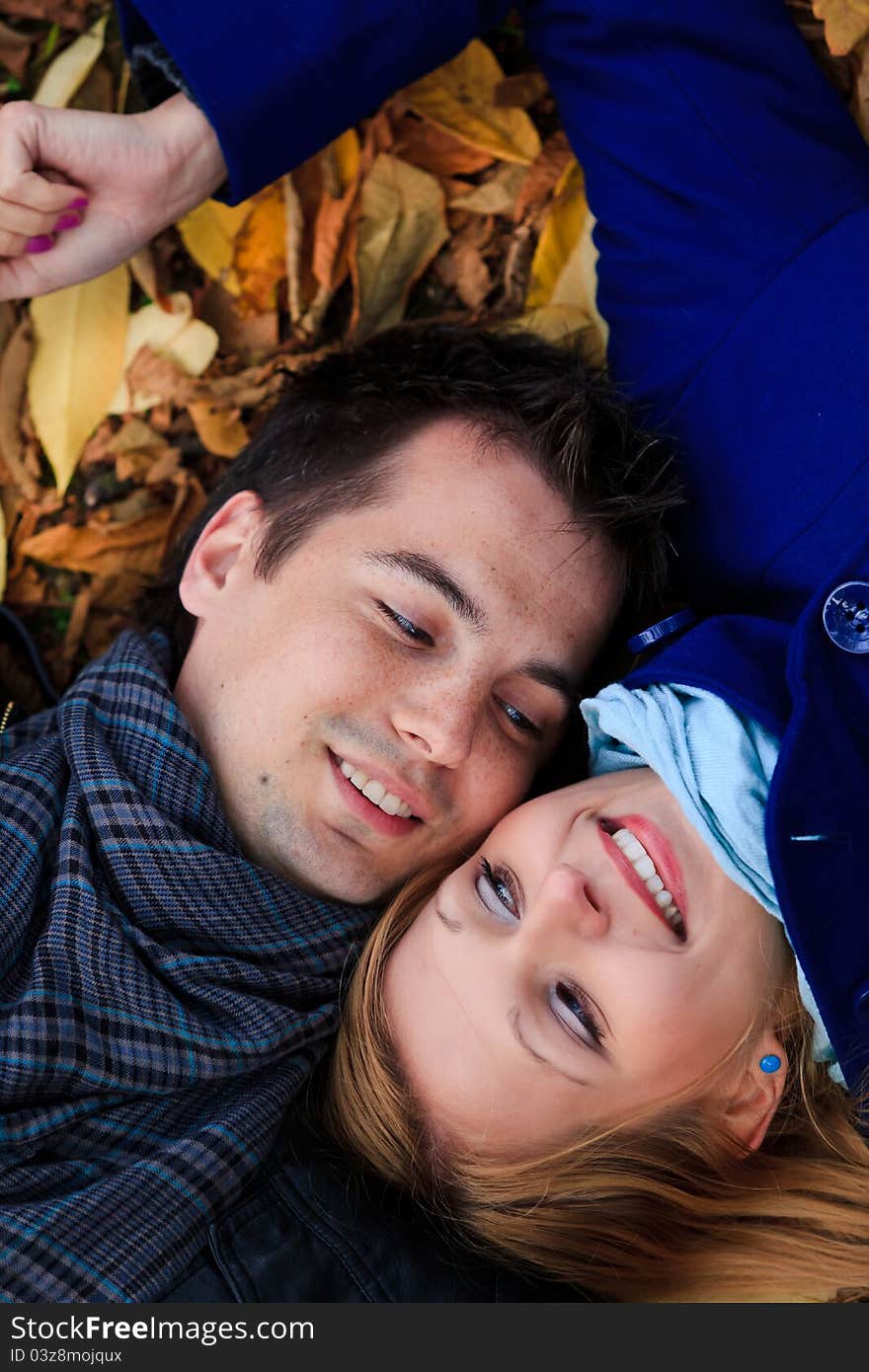 Portrarit of a happy young couple lying on fallen leaves in the park. Portrarit of a happy young couple lying on fallen leaves in the park.