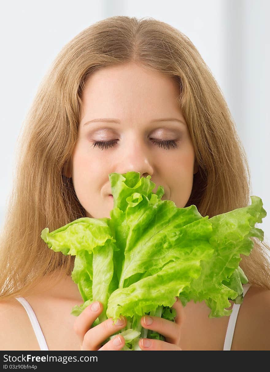 Young beautiful woman with green lettuce with eyes closed. Young beautiful woman with green lettuce with eyes closed