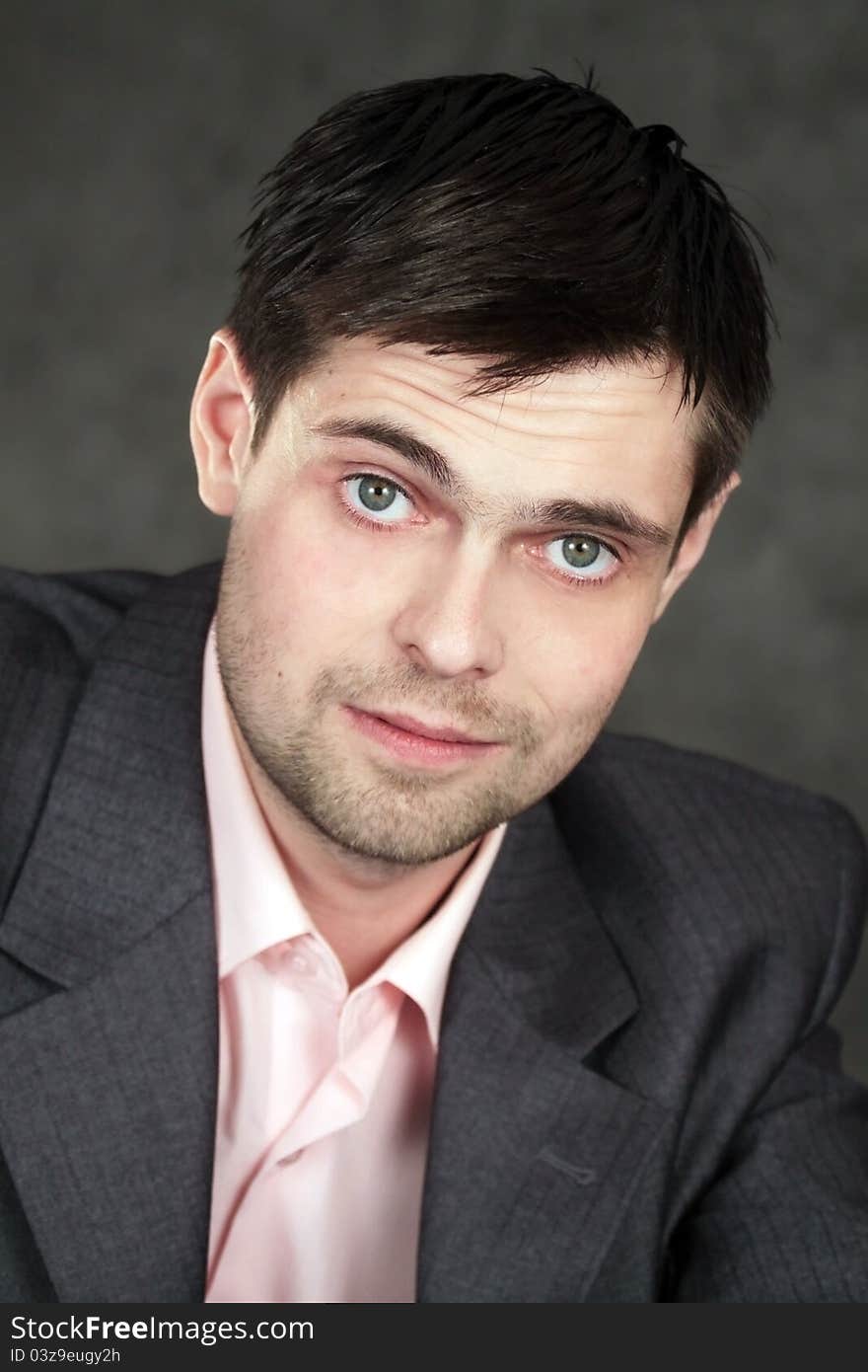 Young business man in gray suit on gray background