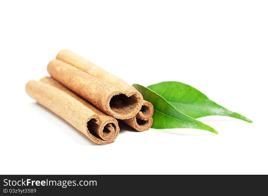 Cinnamon sticks and green leaves on a white background